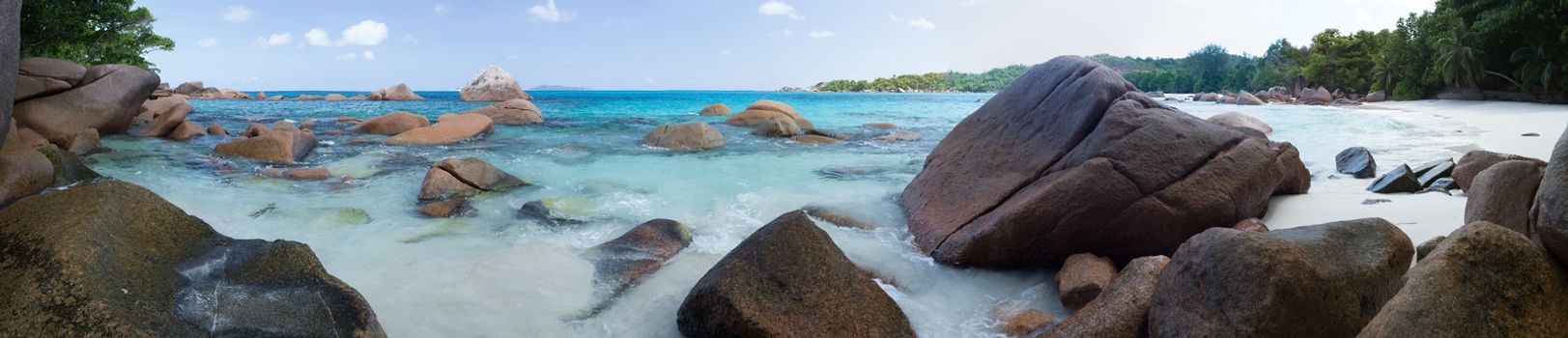 The beach of the Seychelles with blue water and stones