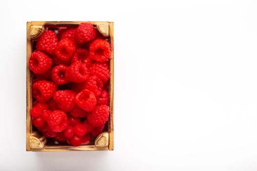 Some raspberries in a small wooden box on a white background