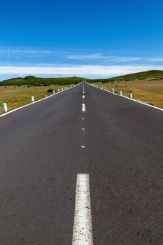 a straight road over the area with a blue sky with any clouds in the distance