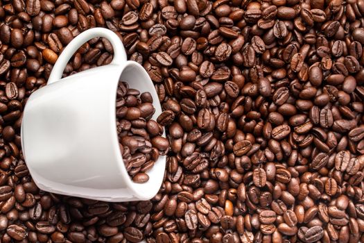 A White cup with coffee beans on a background of coffee beans