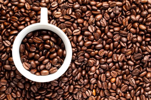A White cup with coffee beans on a background of coffee beans
