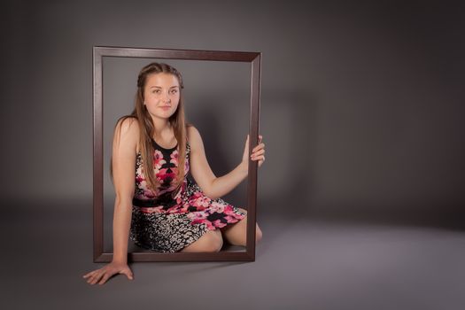Young woman is sitting on floor with a picture frame