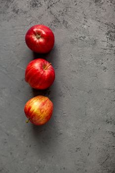 Three Ripe garden red apples on gray concrete. Fruits concept of the fall harvest. Space for text.