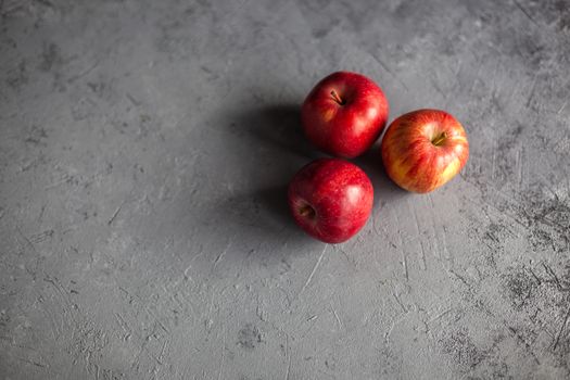 Three Ripe garden red apples on gray concrete. Fruits concept of the fall harvest. Space for text.