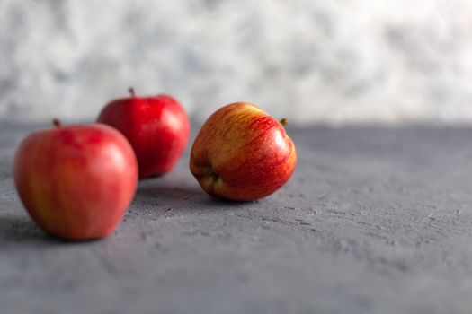 Three Ripe garden red apples on gray concrete. Fruits concept of the fall harvest. Space for text.