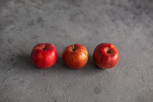 Three Ripe garden red apples on gray concrete. Fruits concept of the fall harvest. Space for text.