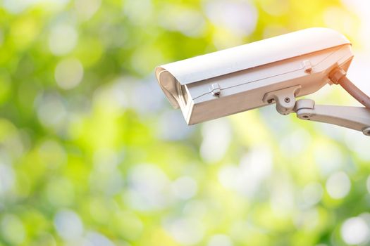 Closeup CCTV or surveillance camera in the garden with colorful green nature background.