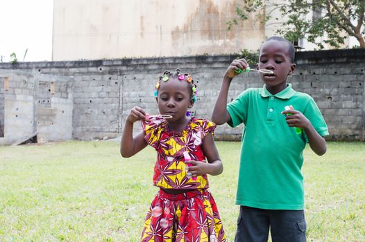 two happy children playing outdoors with soap bubble
