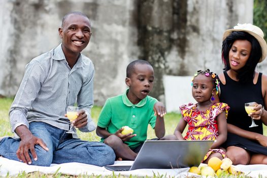 happy family with two children sitting at the park picnicking