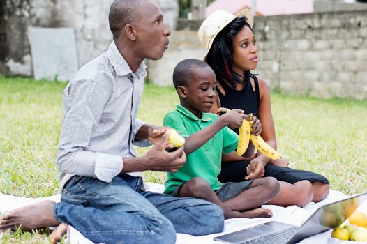 happy family, father, mother and son sitting in the garden picnicking