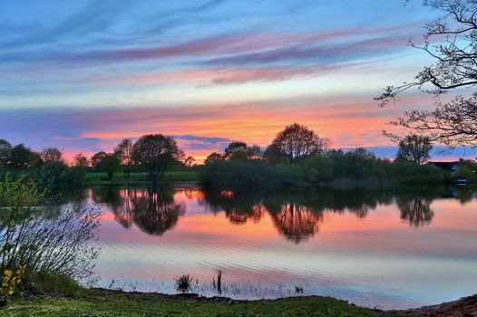 Beautiful sunset landscape at a lake with a reflective water surface.