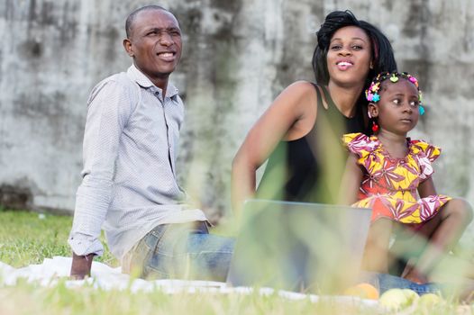 Happy family. Father, mother and child sitting in green grass