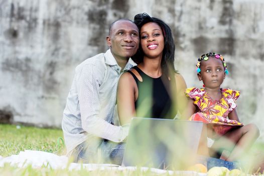 Happy family. Father, mother and child sitting in green grass