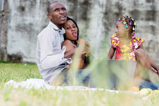 Happy family. Father, mother and child sitting in green grass