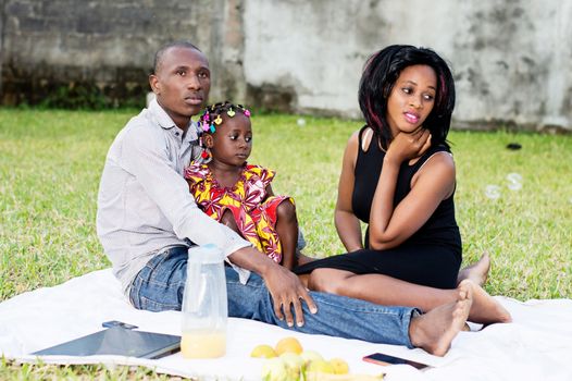 family sitting in group picnic and playing together outside