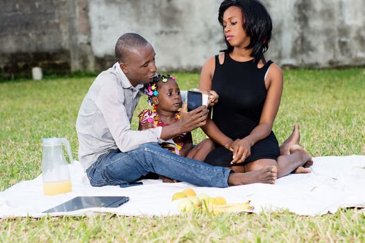 Good family sat on the grass in the park with their child and played together during the picnic