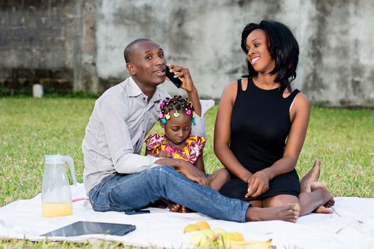 Good family sat on the grass in the park with their child and played together during the picnic