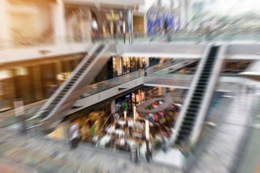 The abstract blurred people inside the shopping mall; filter radial blur zoom effect.