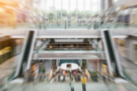 The abstract blurred people inside the shopping mall; filter radial blur zoom effect.