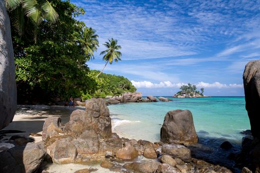 Beach with blue water and blue sky and white sand and some rocks