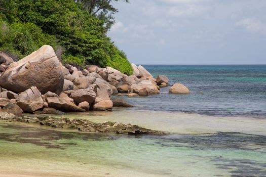 Beach with blue water and blue sky and white sand and some rocks