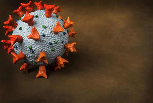 Homemade realistic model of Corona Virus SARS-CoV-2 used as a tool for science education for students in school. Dangerous coronavirus caused global pandemy in COVID-19 respiratory disease. On a brown background