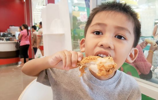 Cute Asian boy eating fried chicken is delicious.