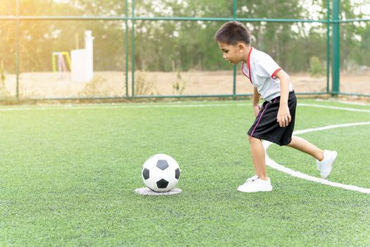 The boy was playing soccer on the football field with happiness.