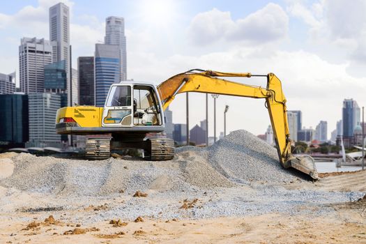 Excavator parked on the mound in the city with skyscraper background.