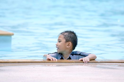 Asian boy in swimwear, swimming fun in the pool.