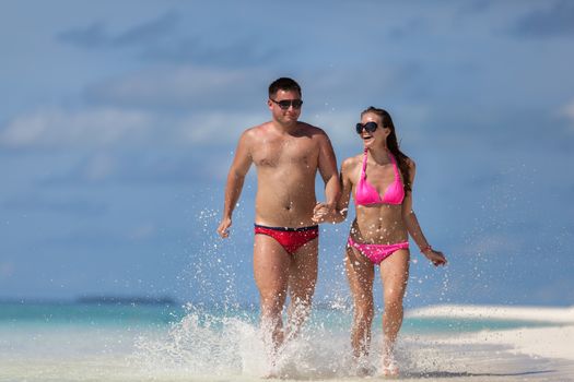 Maldives, a couple is running on the beach