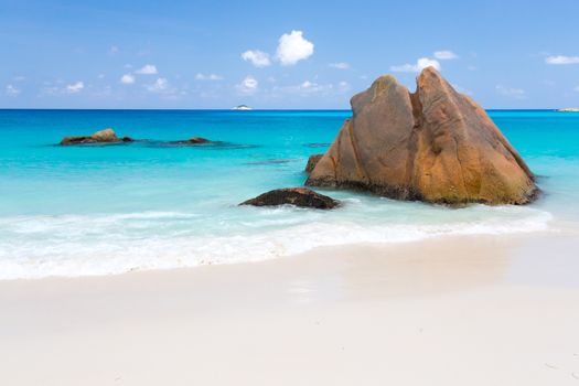 Beach with blue water and blue sky and white sand and some rocks