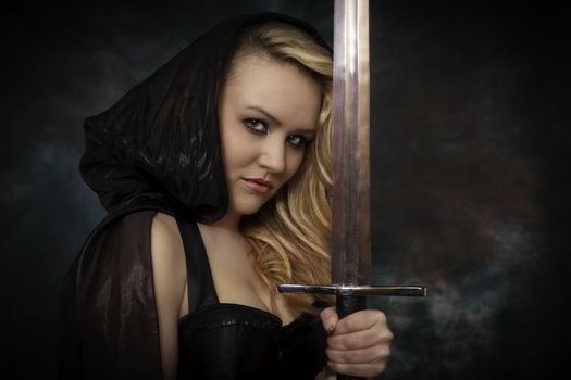 young beautiful woman with a sword in the hand in black cape. Amazon woman