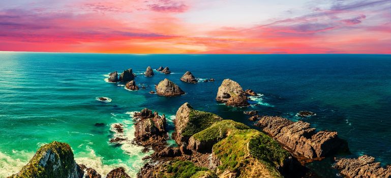 Sunset over Nugget Point which is located in the Catlins area on the Southern Coast of New Zealand. There area many rock islands - nuggets - in the sea. Panoramic photo