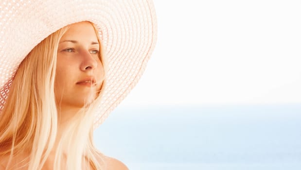 Woman with blond hair wearing hat, enjoying seaside and beach lifestyle in summertime, holiday travel and leisure concept