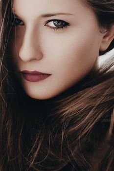 Closeup beauty portrait of a woman with classy makeup look and perfect skin, brunette girl with long healthy brown hair, female model posing for luxury cosmetics or luxe skincare brands