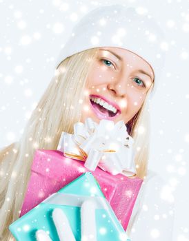 Christmas surprise and glitter snow background, happy blonde girl with gift boxes in winter season for shopping sale and holiday brands