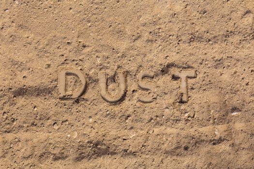 the word dust embossed on dusty road surface - close-up flat lay perspective under direct sunlight