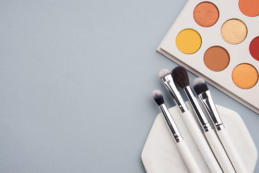 Palette with shadows and professional brushes on a stand on a gray background. High quality photo