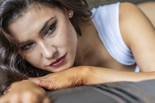 A gorgeous brunette model poses in lingerie in a bedroom environment