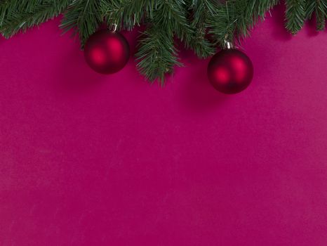 Merry Christmas and happy New Year on a red background with evergreen branches plus ball ornaments 