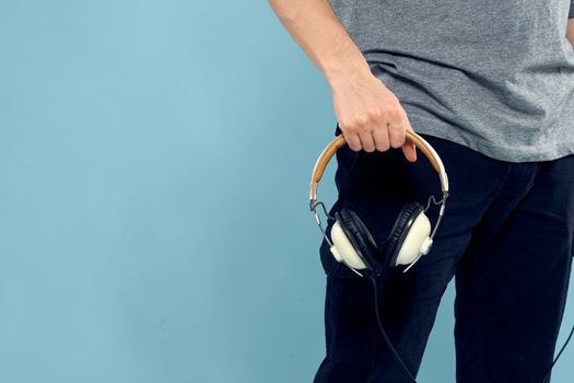 Headphones in man hands cropped view music technology blue background. High quality photo