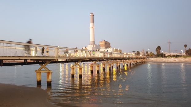 North Tel-Aviv at sunset wit people passing the bridge by foot and bicycles