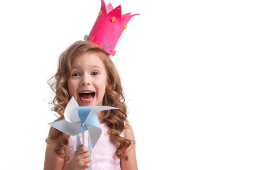 Beautiful little candy princess girl in crown holding pinwheel and smiling