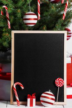 Blank blackboard and Christmas tree branches, red glass ball and candy canes