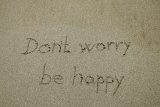 Don't worry be happy written on a sand. Don't worry, be happy.