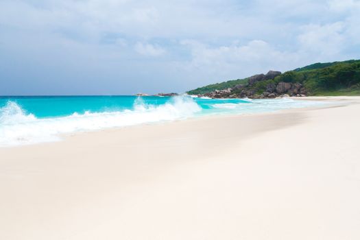 The beach on the Seychelles with white sand turquoise water and blue sky