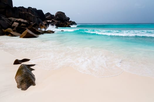 Blue sky and a white sand beach with a lot of big rocks