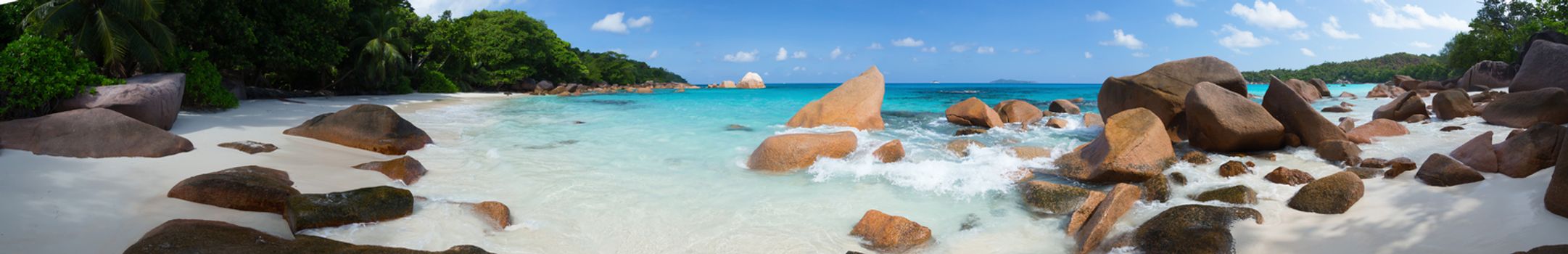 Panorama of the beach with big stones and white sand and a blue sky