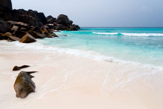 Blue sky and a white sand beach with a lot of big rocks